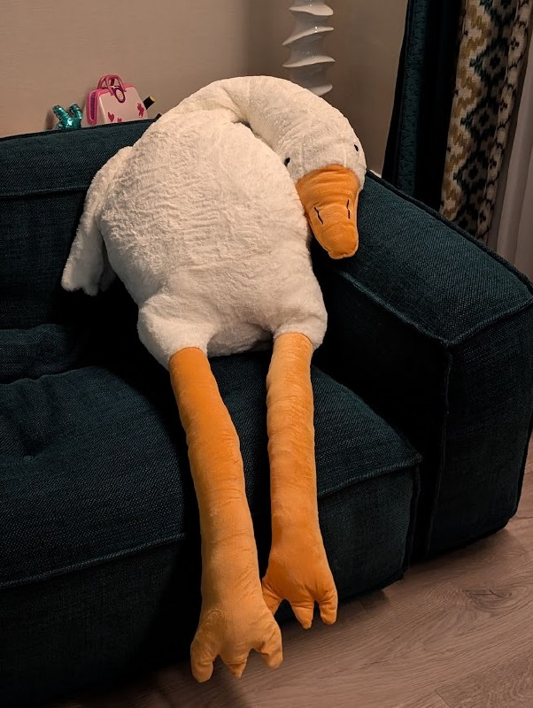 A photo of a giand plush gooze lying on a sofa